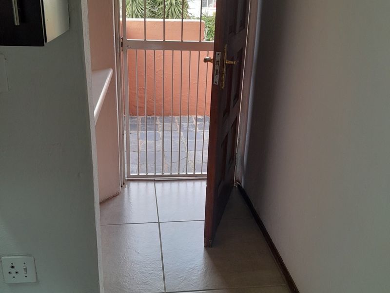 An entrance area featuring tiled flooring, a timber door, and a security gate leading to an outdoor space.
