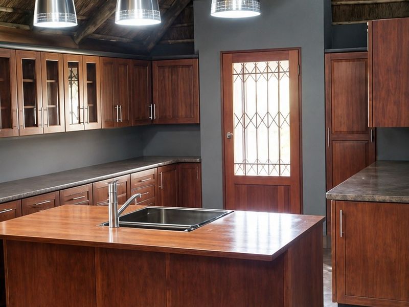 A spacious kitchen featuring wooden cabinetry, a central island with a sink, pendant lighting, and a distinctive vaulted thatch ceiling.