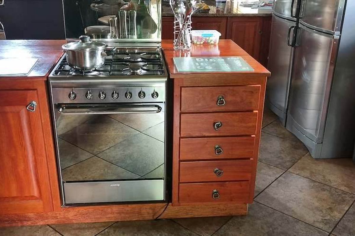 A kitchen island featuring a built-in gas hob and oven, complemented by wooden cabinetry and tiled flooring.
