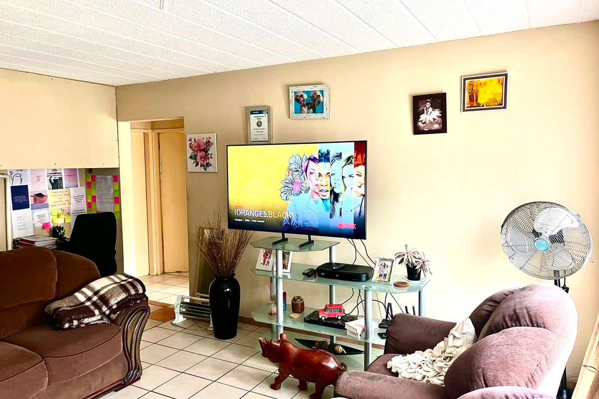 A living room area featuring tiled flooring and a textured ceiling, providing a functional space for relaxation.