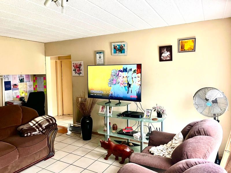 A living room area featuring tiled flooring and a textured ceiling, providing a functional space for relaxation.
