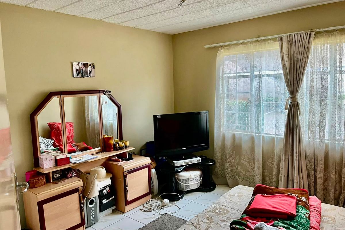 A bedroom featuring tiled flooring and a window with natural light, currently requiring cosmetic updates to modernize the space.