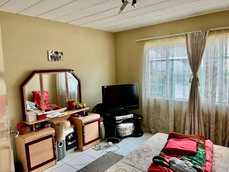 A bedroom featuring tiled flooring and a window with natural light, currently requiring cosmetic updates to modernize the space.