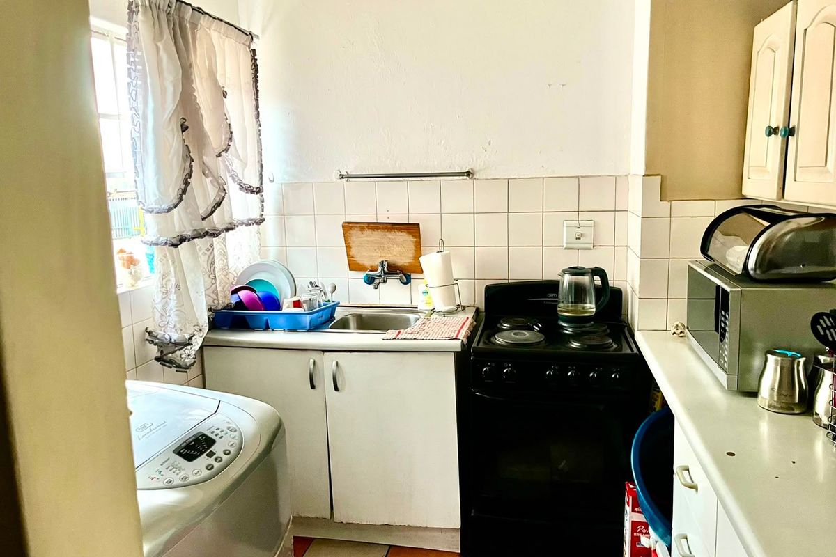 Compact kitchen featuring a stainless steel sink, tiled backsplash, and freestanding stove, offering functional space with potential for modern updates.