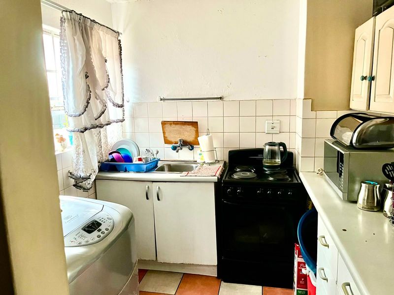 Compact kitchen featuring a stainless steel sink, tiled backsplash, and freestanding stove, offering functional space with potential for modern updates.