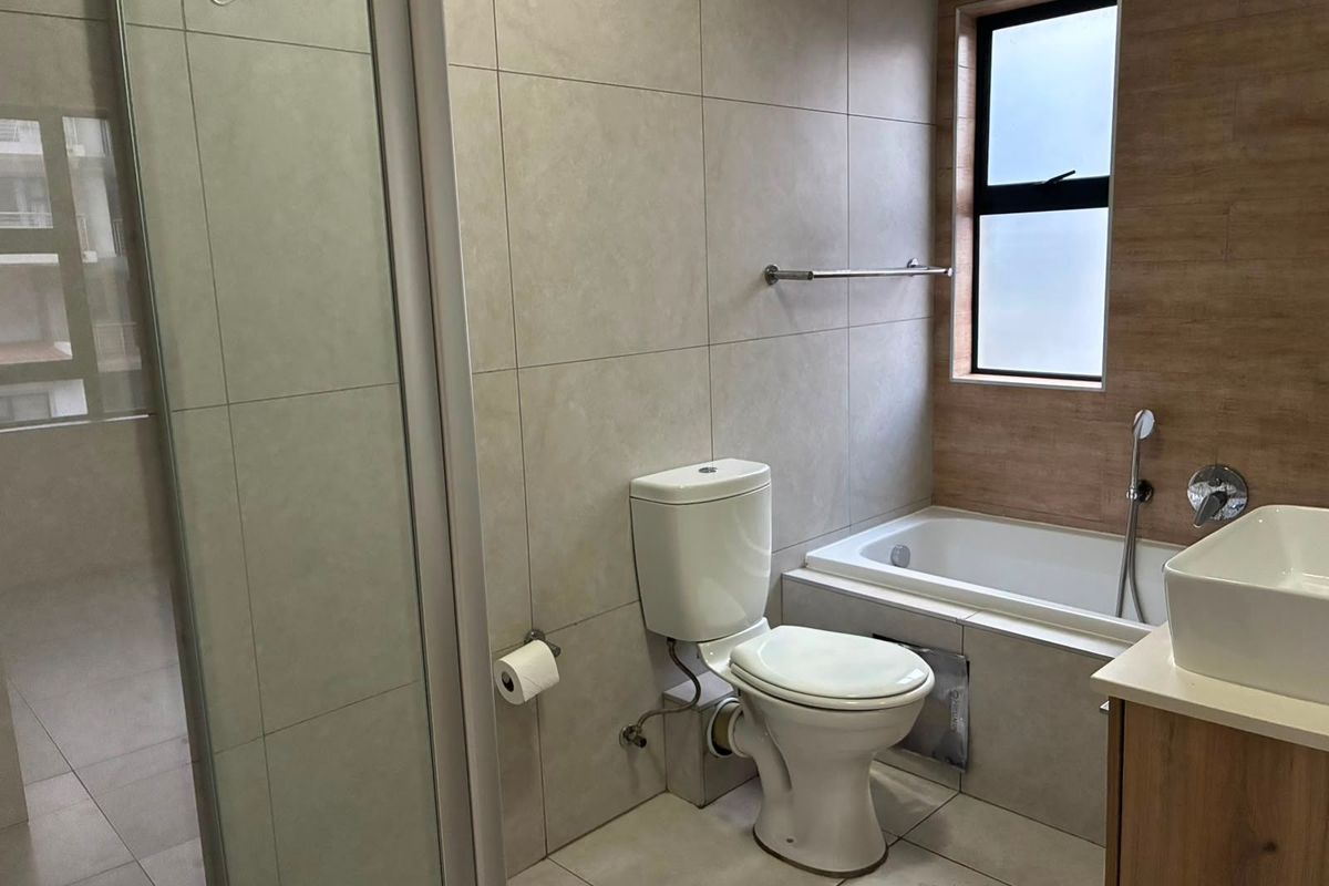 Modern bathroom featuring a shower enclosure, bathtub, vessel sink with vanity, and neutral floor-to-ceiling tiling.