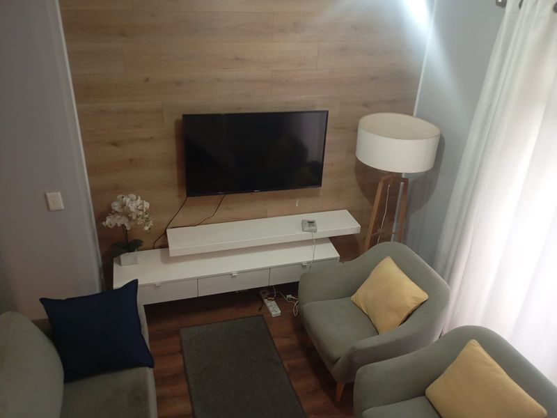 A cozy living room area featuring wood-look wall paneling and laminate flooring, creating a warm and inviting atmosphere.