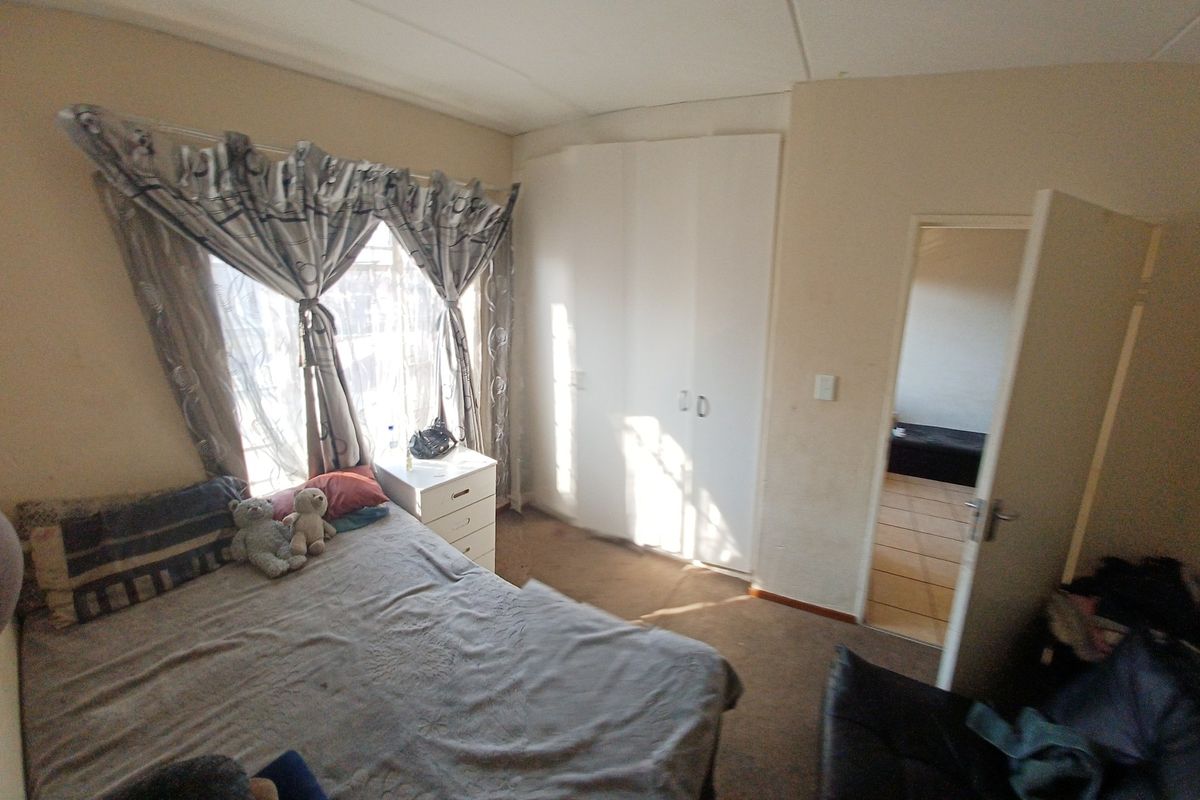 A bedroom featuring built-in wardrobes and carpet flooring, offering a functional space with potential for cosmetic updates.