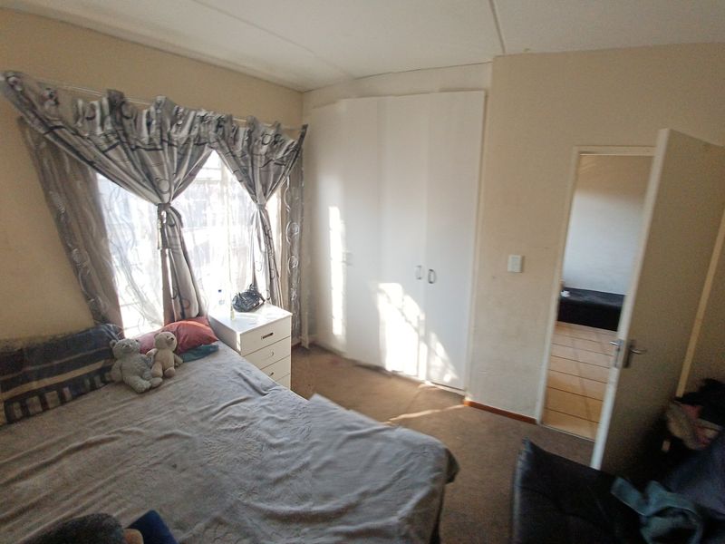 A bedroom featuring built-in wardrobes and carpet flooring, offering a functional space with potential for cosmetic updates.
