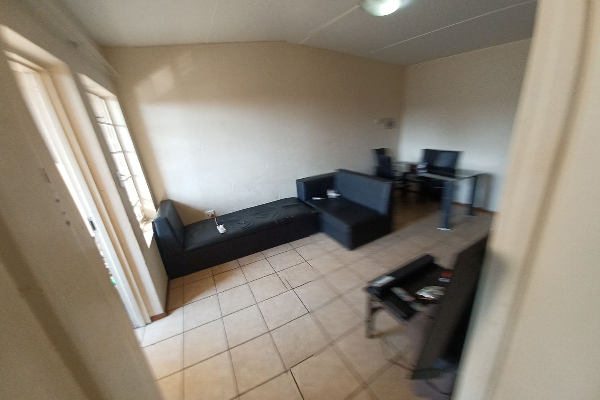 A living room area featuring tiled flooring and a sliding glass door, requiring cosmetic updates to improve the overall aesthetic and condition.