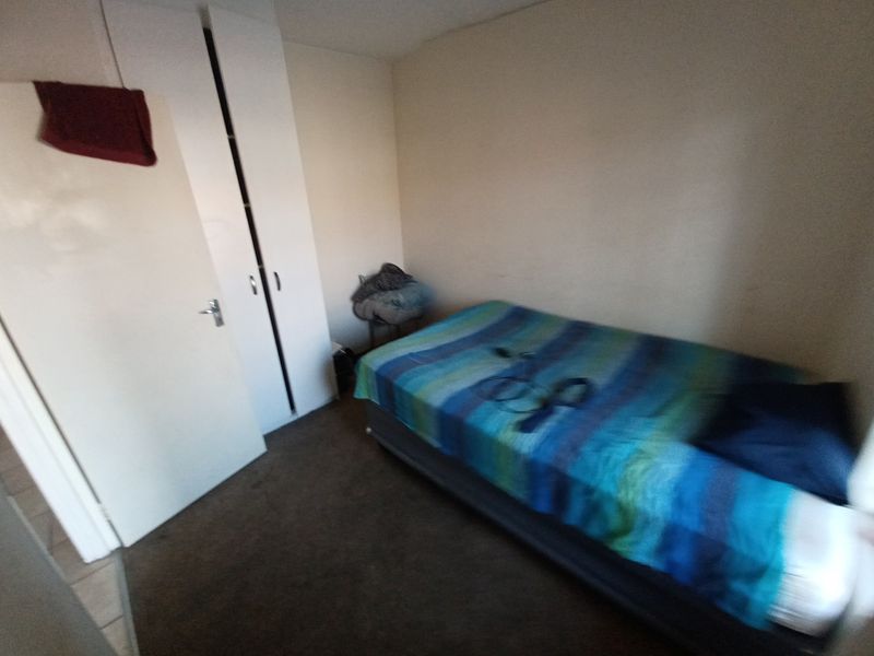 A compact bedroom featuring a built-in wardrobe and carpeted flooring, requiring cosmetic updates to improve its overall appeal.