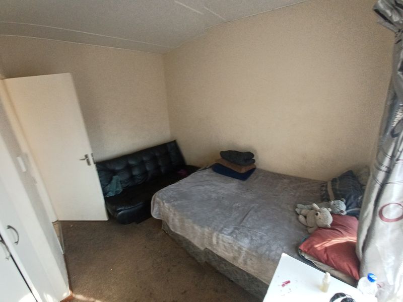A compact bedroom featuring a built-in cupboard and neutral wall finishes, requiring cosmetic updates to the flooring and paintwork.