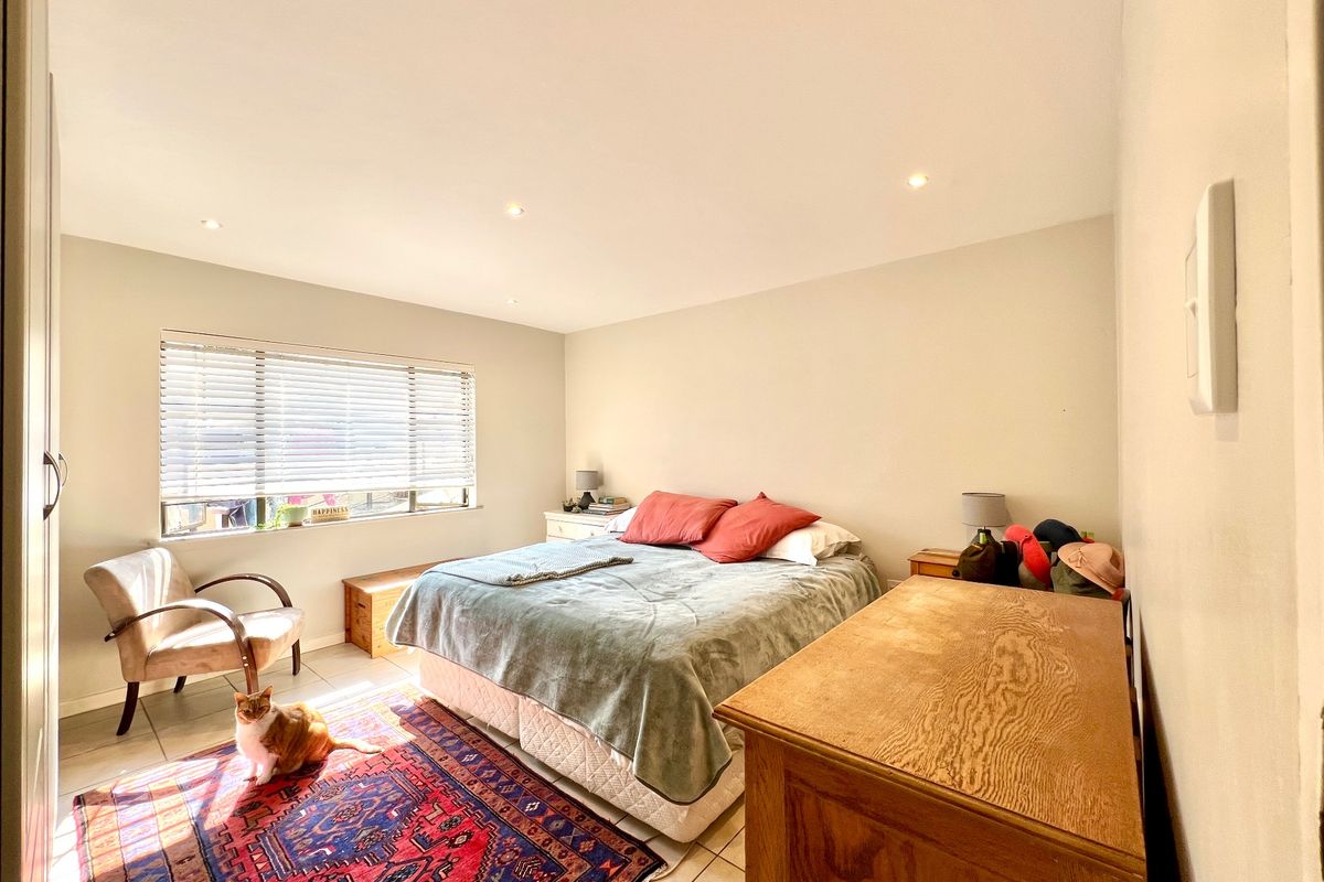 A well-lit bedroom featuring tiled flooring, recessed downlights, and venetian blinds, offering a comfortable and functional living space.