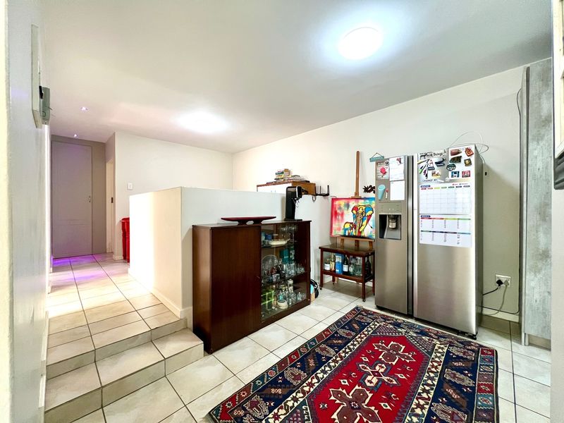 A living area featuring ceramic tiled flooring, a raised floor section, and neutral wall finishes, providing a functional and open layout.