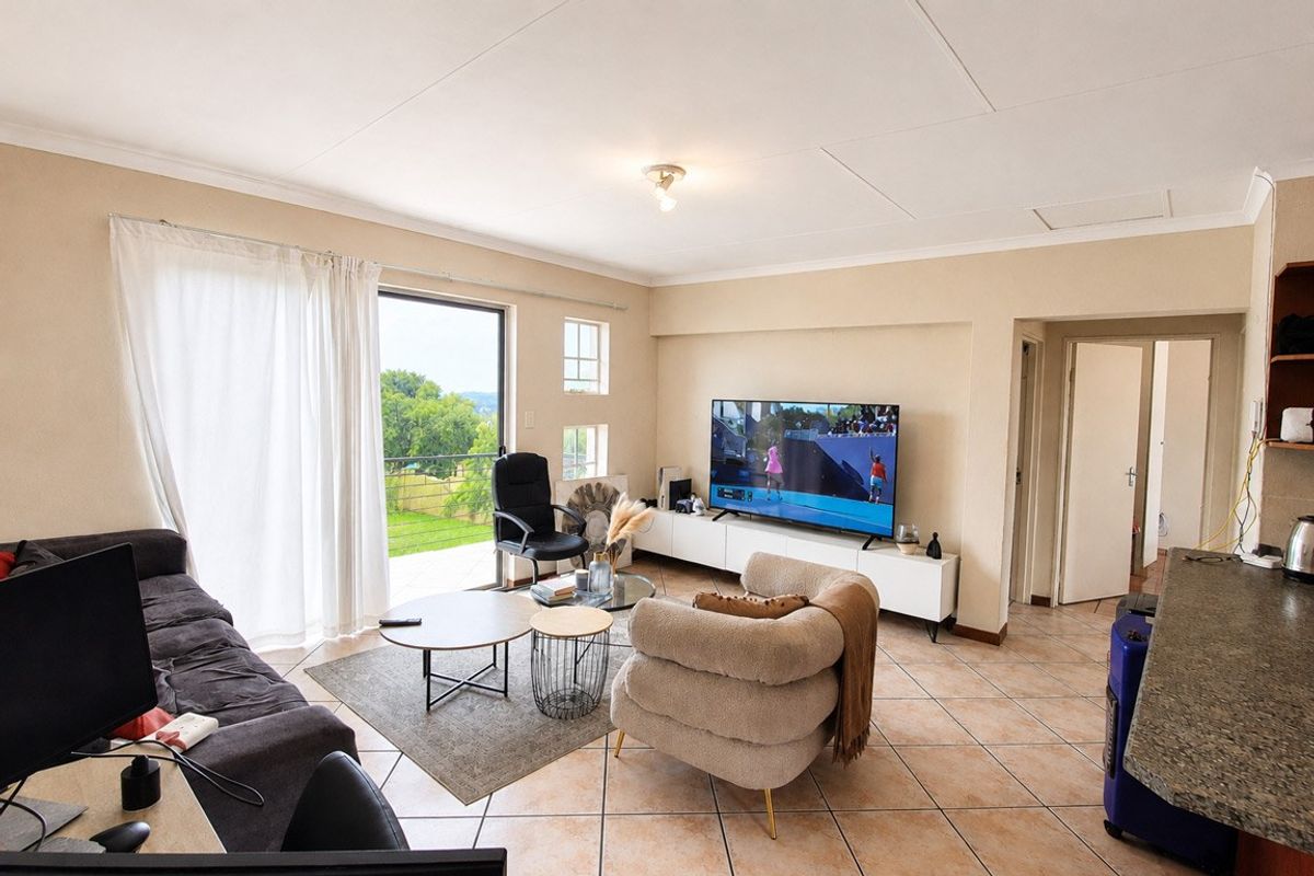 A bright living room featuring tiled flooring, coved ceilings, and a sliding glass door providing access to an outdoor balcony area.