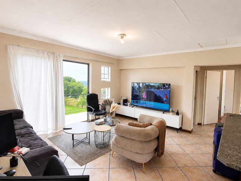 A bright living room featuring tiled flooring, coved ceilings, and a sliding glass door providing access to an outdoor balcony area.