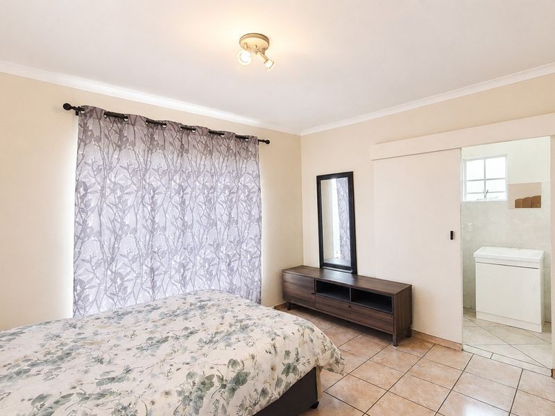 A bedroom featuring tiled flooring, coving, and a sliding door providing direct access to an en-suite bathroom.