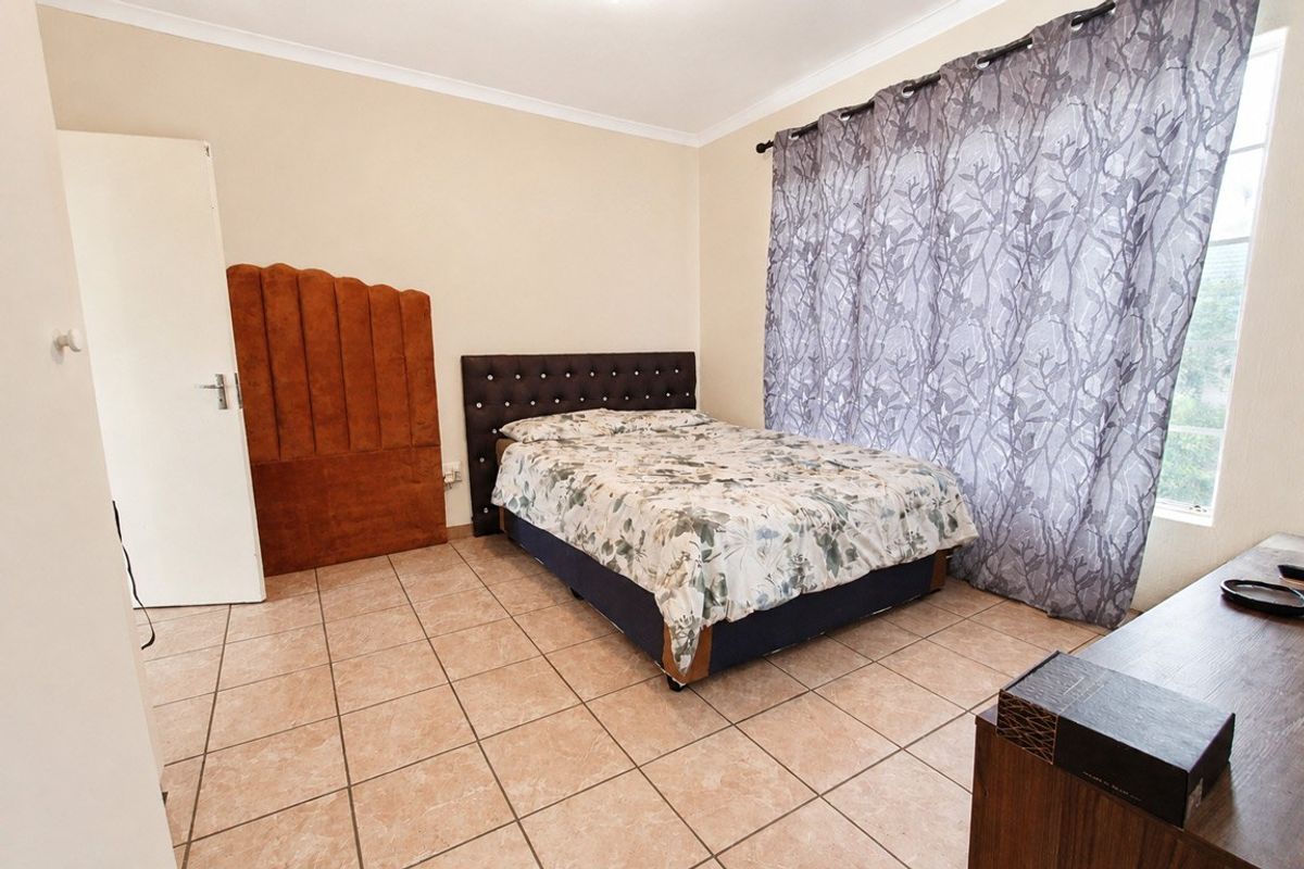 A bedroom featuring tiled flooring and neutral wall finishes, providing a functional space with natural light.