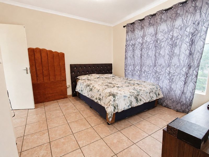 A bedroom featuring tiled flooring and neutral wall finishes, providing a functional space with natural light.