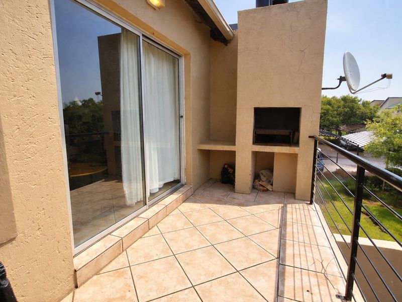 A private balcony featuring a built-in braai, tiled flooring, and sliding door access, offering an ideal space for outdoor entertaining.