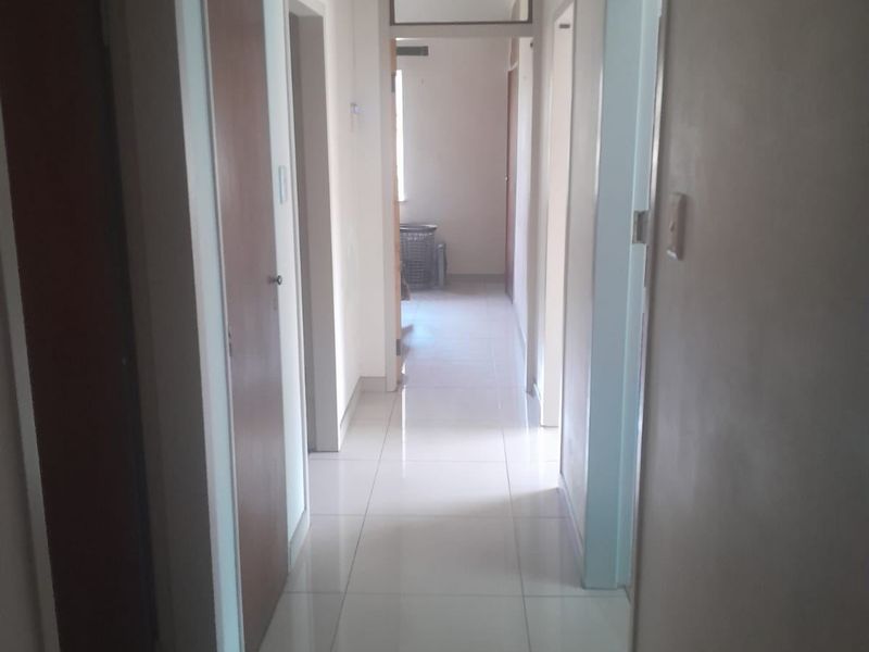 A functional hallway featuring tiled flooring and built-in storage cupboards, providing access to multiple rooms within the home.