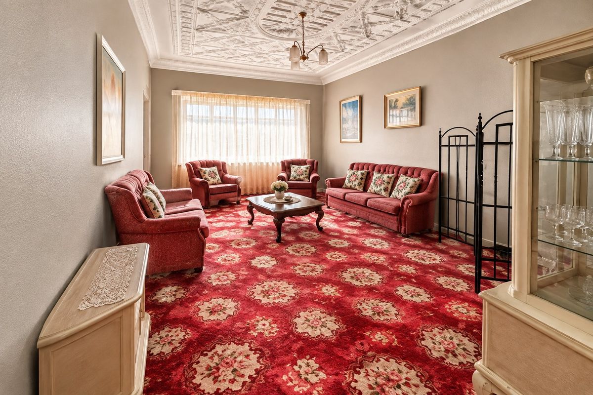 Spacious living room featuring an ornate plaster ceiling, coving, and large windows, offering a classic aesthetic with potential for modern updates.
