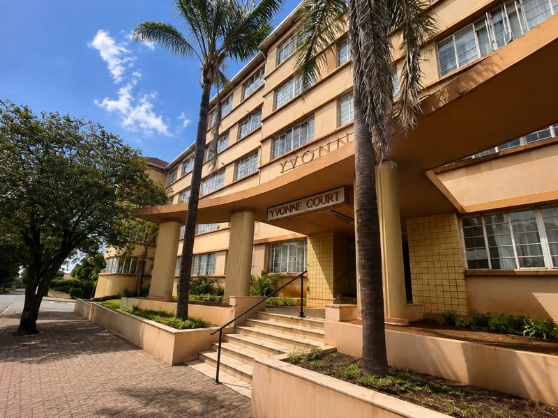 Front elevation of Yvonne Court apartment building featuring a classic architectural facade, concrete entrance staircase, and established palm trees.