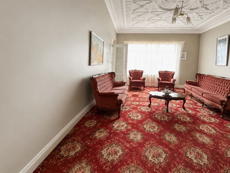 Spacious living room featuring an ornate plaster ceiling with a central rose and traditional patterned carpeting.