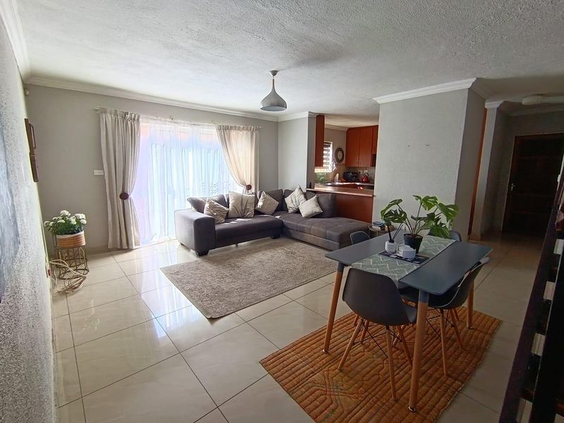 Open-plan living and dining area featuring tiled floors, sliding door access to the exterior, and a semi-open kitchen with built-in cabinetry.