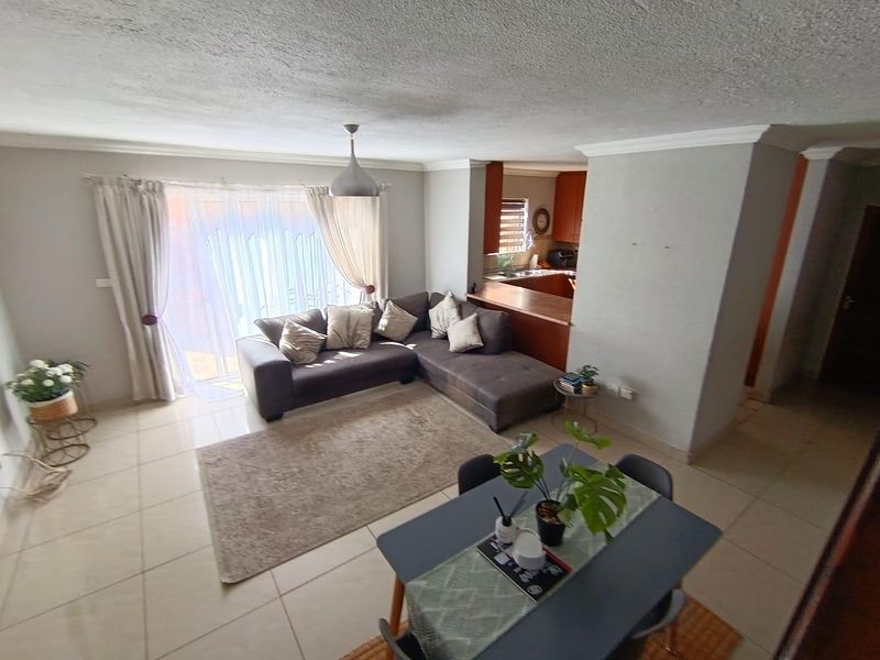 Open-plan living and dining area featuring tiled floors, a breakfast bar connecting to the kitchen, and sliding door access to the exterior.