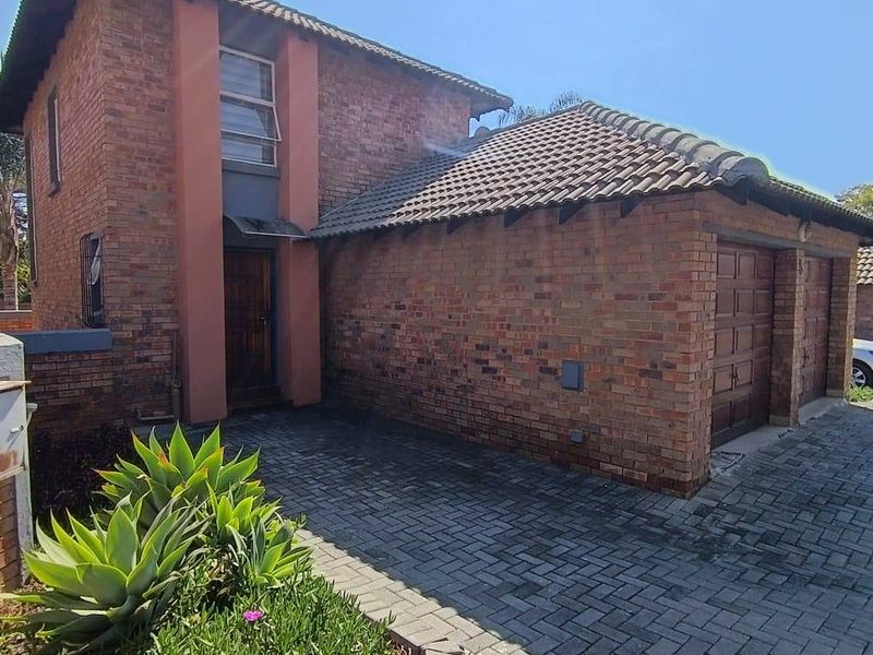 Front elevation of a double-story face brick townhouse featuring a paved driveway and double garage.