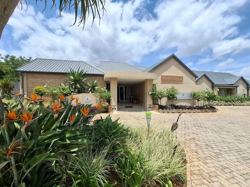 Front elevation of the residential property featuring a paved driveway, covered entrance, and well-maintained landscaped garden.