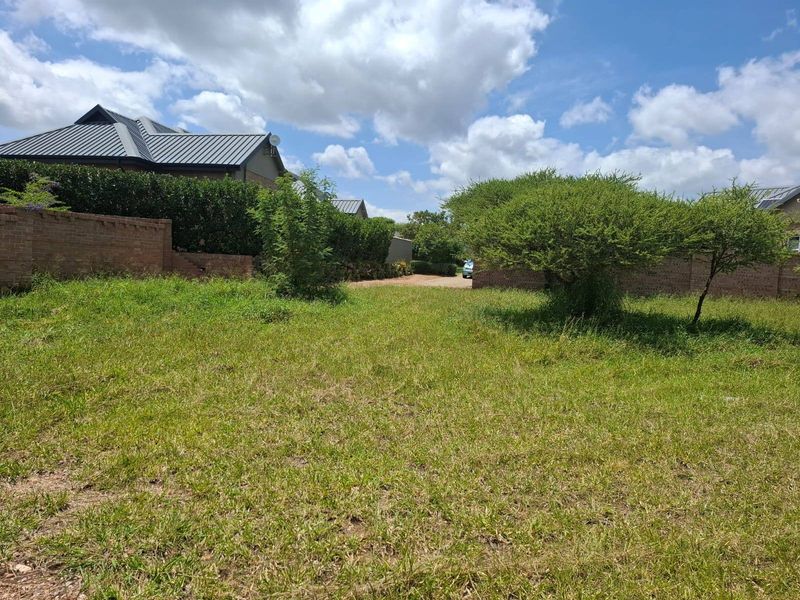 A vacant residential plot featuring established trees and brick boundary walls, offering a clear space for potential development.