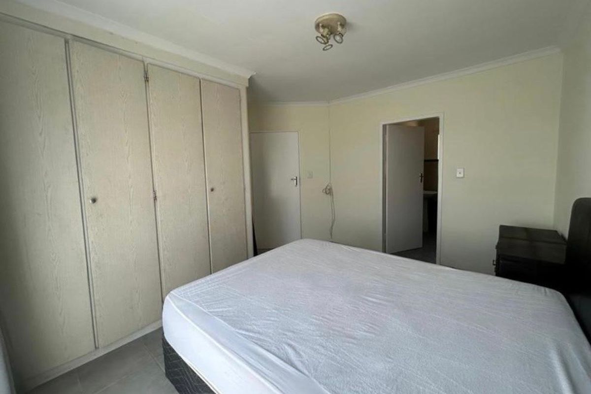 A functional bedroom featuring built-in cupboards, tiled flooring, and coved ceilings, offering a neutral canvas for potential interior updates.