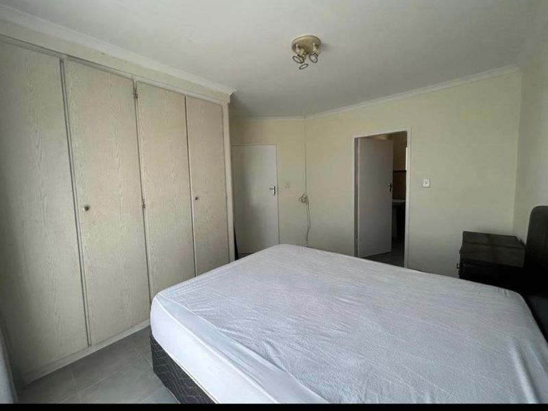 A functional bedroom featuring built-in cupboards, tiled flooring, and coved ceilings, offering a neutral canvas for potential interior updates.