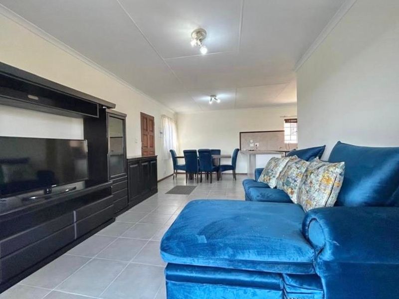 Spacious open-plan living and dining area featuring tiled flooring, neutral walls, and a functional kitchen breakfast bar, offering a versatile layout for modern living.