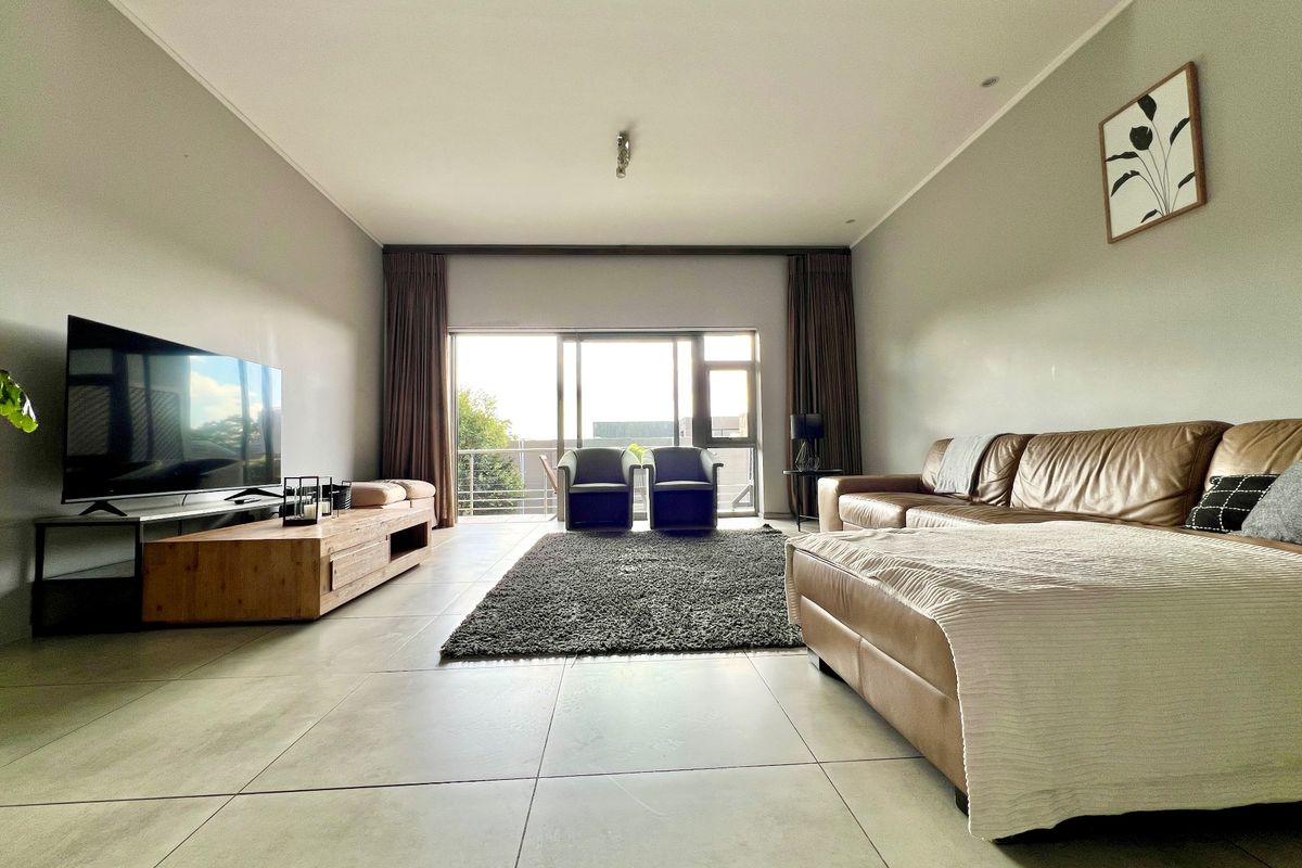 Spacious living room featuring large format floor tiles, a recessed ceiling, and expansive sliding glass doors leading to a balcony.