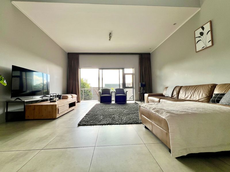Spacious living room featuring large format floor tiles, a recessed ceiling, and expansive sliding glass doors leading to a balcony.