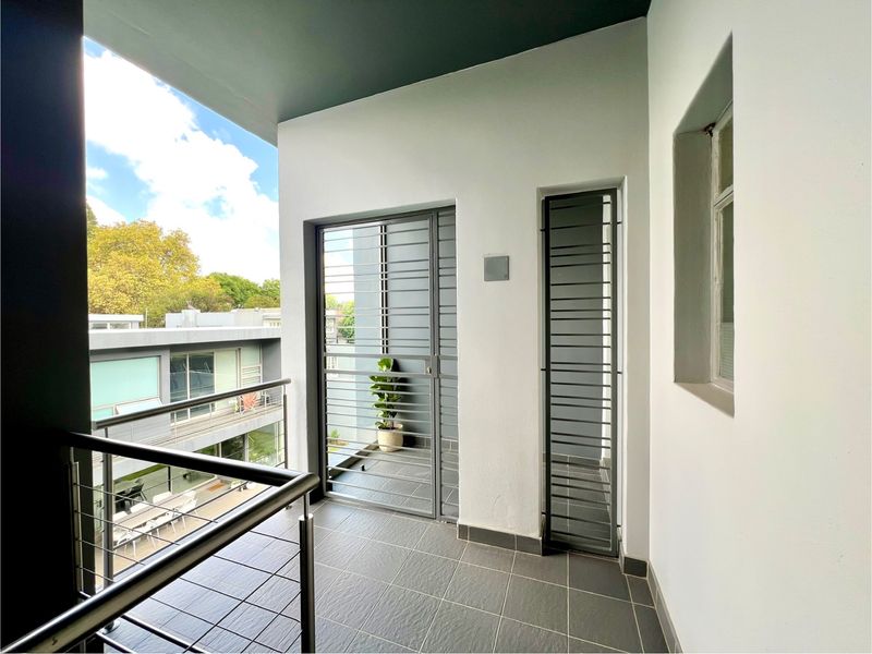 A modern, well-maintained balcony featuring tiled flooring, stainless steel balustrades, and secure metal gates, offering a clean outdoor space.