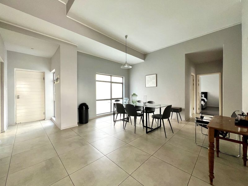 Spacious open-plan living and dining area featuring neutral tiled flooring, modern recessed ceiling details, and ample natural light.