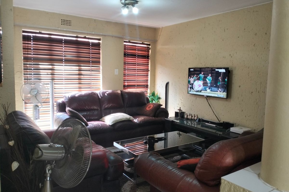 A living room featuring textured walls, venetian blinds, and a wall-mounted television, offering a functional space for relaxation.
