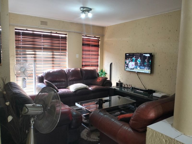 A living room featuring textured walls, venetian blinds, and a wall-mounted television, offering a functional space for relaxation.