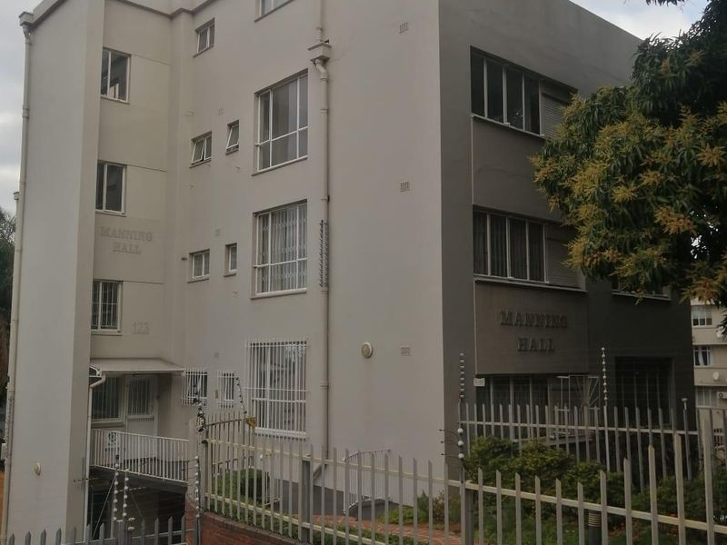 Exterior view of Manning Hall apartment building featuring a multi-story facade, secure perimeter fencing, and integrated security measures.
