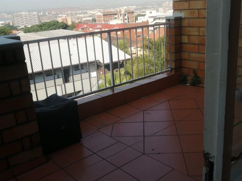 A private balcony featuring tiled flooring, a metal balustrade, and face brick accents, offering an elevated urban view.
