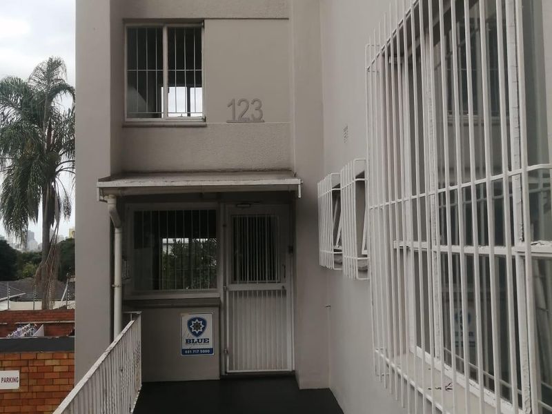 Exterior view of the Manning Hall apartment building entrance, featuring security bars and a gated access point.