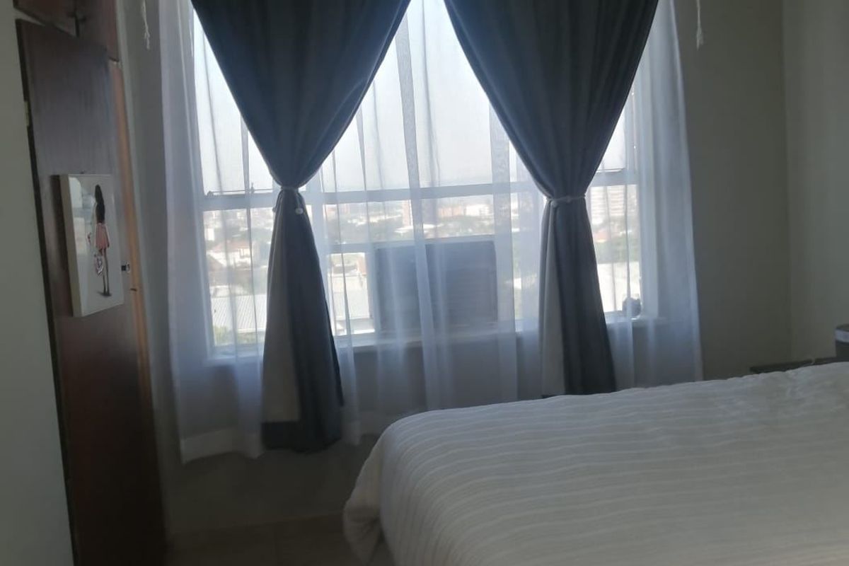 A bedroom featuring tiled flooring, a built-in wardrobe, and a window-mounted air conditioning unit.
