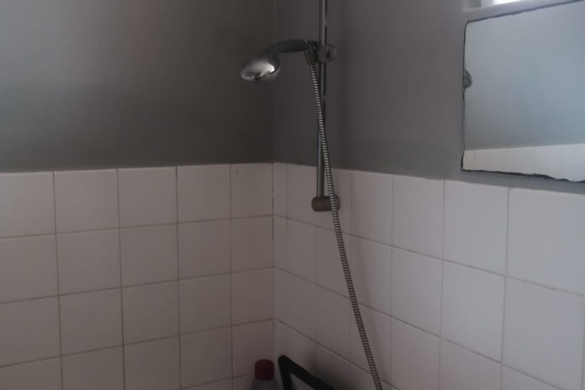 A functional bathroom featuring a bathtub with a handheld shower attachment, tiled splashback, and a basin.