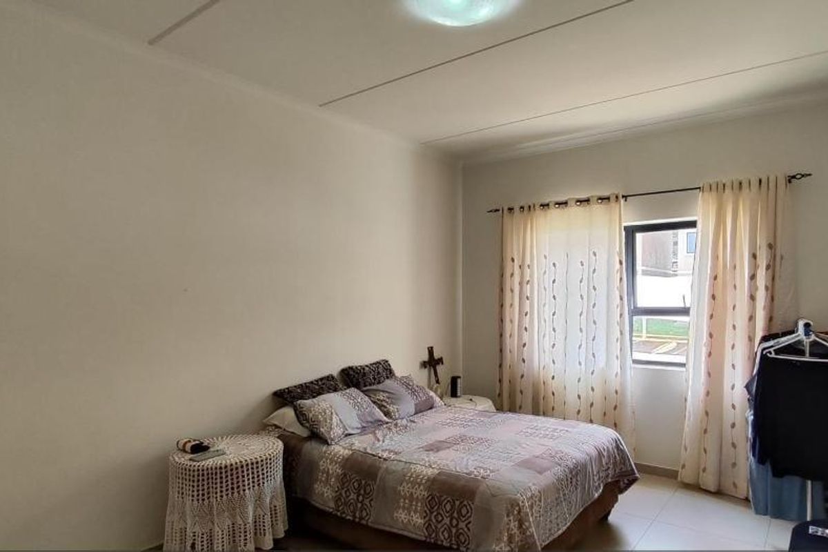 A functional bedroom featuring tiled flooring and a window with curtain tracks, offering a neutral space ready for personalization.