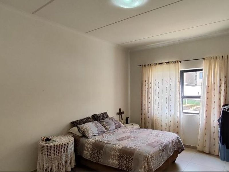 A functional bedroom featuring tiled flooring and a window with curtain tracks, offering a neutral space ready for personalization.