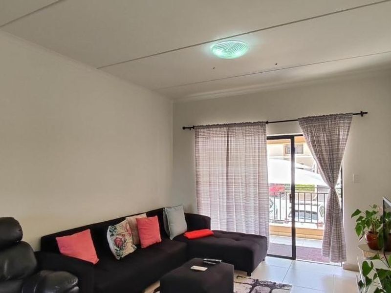 A comfortable living room featuring tiled flooring and a sliding glass door that provides access to an outdoor balcony area.